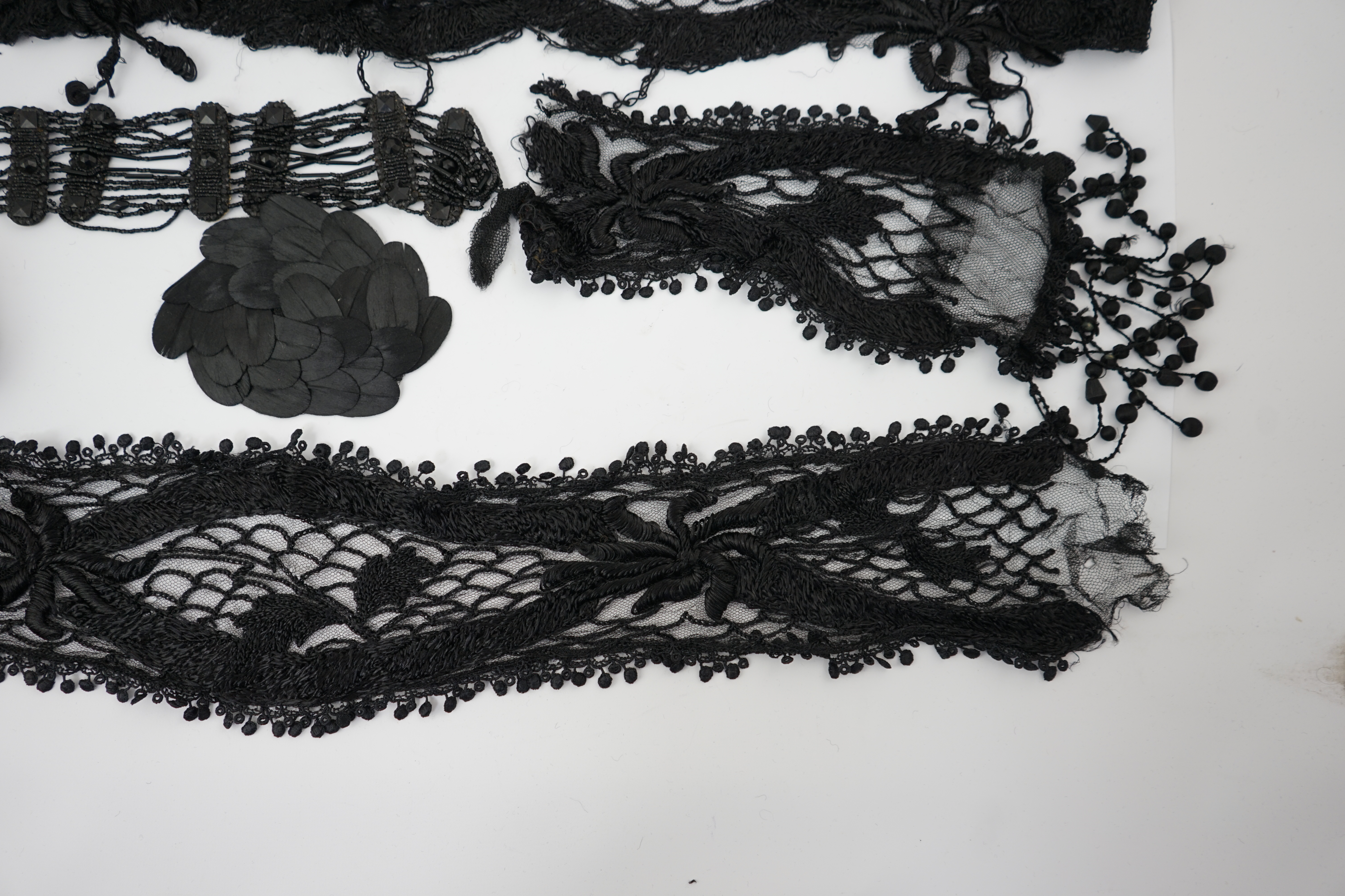 An 1930's black sequin cape, trimmings and lace, an Art Deco black sequin decorated cape on black net, an Edwardian jet beaded belt, a Spanish silk fall cap, three panels of black machine lace, a long length black and cr